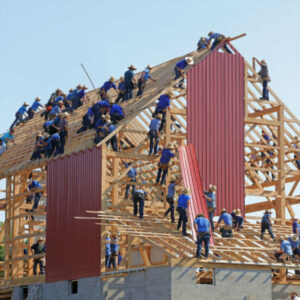 Bild von Zimmermännern, die ein Haus aus Holz bauen als Bild für gute Zusammenarbeit im Team